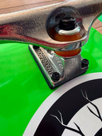 Close-up of a polished silver Independent skateboard truck mounted to a bright green skateboard deck, showing the orange bushings, black hardware and part of the 'ROB ROSKOPP' deck graphic.