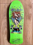 A bright lime green Salva skateboard deck with a detailed psychedelic graphic of a woman in a bikini standing on a cauldron, surrounded by stars, moons, and the word 'Salva' in stylized lettering, photographed flat on a wooden floor.