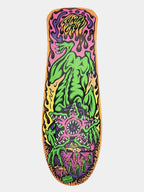 A skateboard deck featuring a highly detailed, colorful psychedelic graphic of a green monster with sharp teeth, set against a pink and purple background with yellow flames, shown on a light gray background.